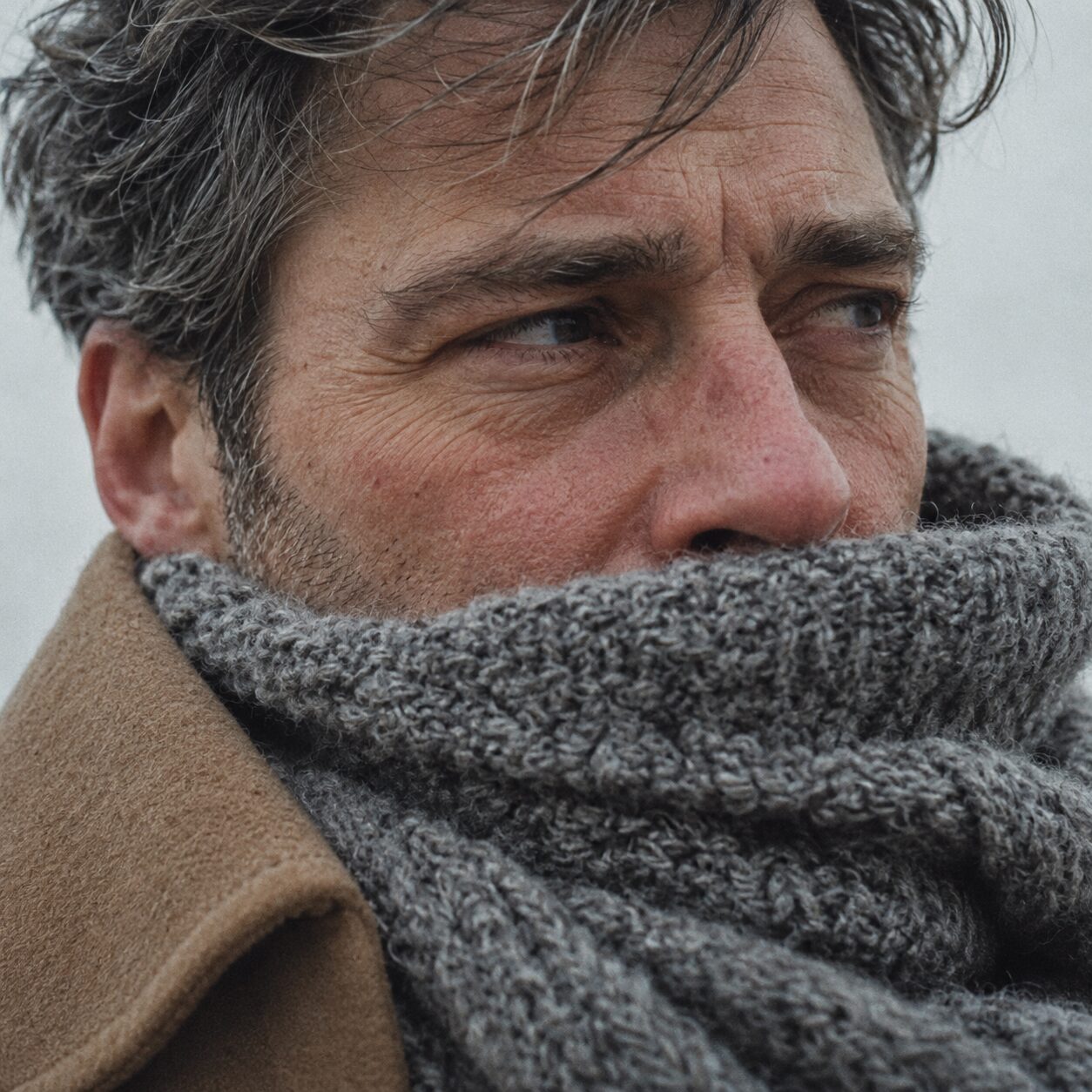 Mann mit Strickschal im Winterwind